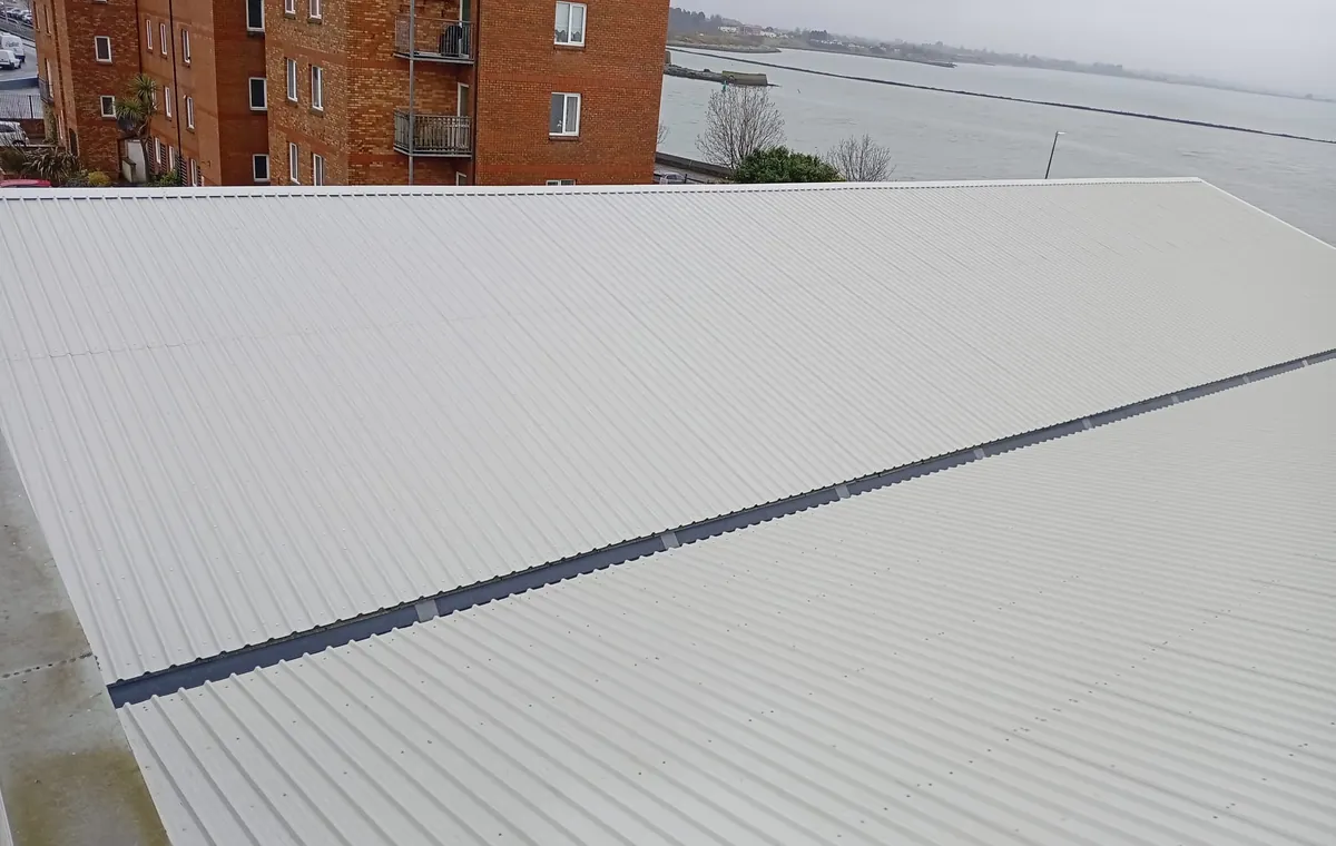 A light corrugated roof with a ridge, apartments behind